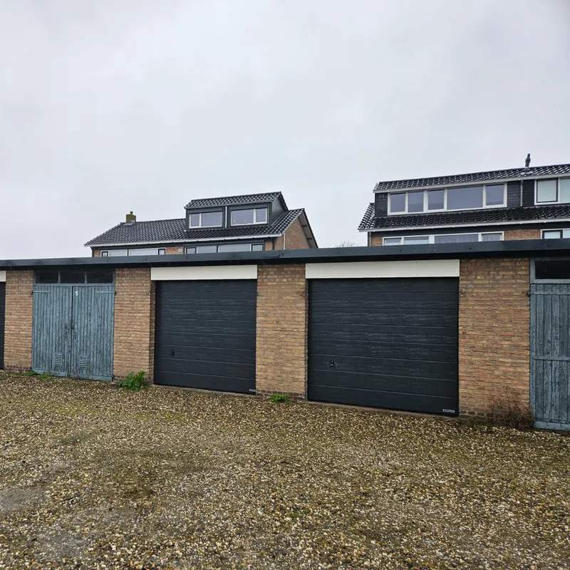 Rij garages waar de oude houten deuren zijn vervangen door nieuwe garagedeuren