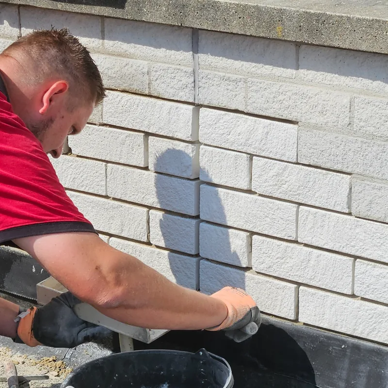 Metselwerk wordt teruggezet onderaan een muur op een plat dak