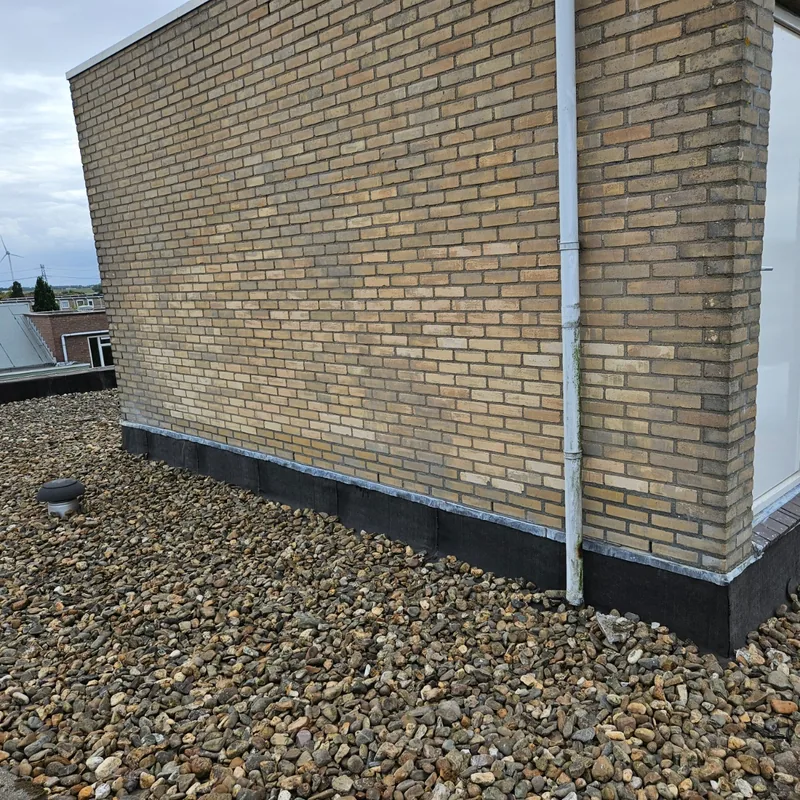 Muur op een plat dak met een nieuwe aansluiting van lood en dakbedekking