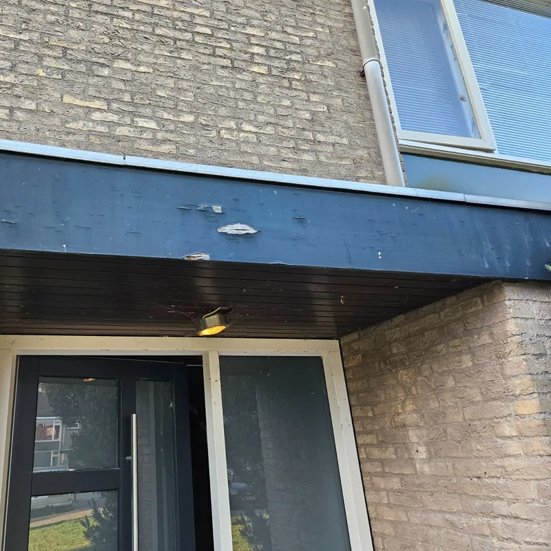 Oude luifel boven de voordeur met loszittende verf, voor de vervanging